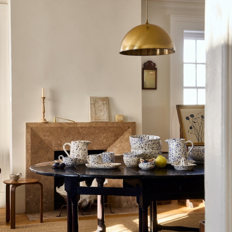 Dining room with a table set for a meal, featuring various dishes and a gold pendant light.