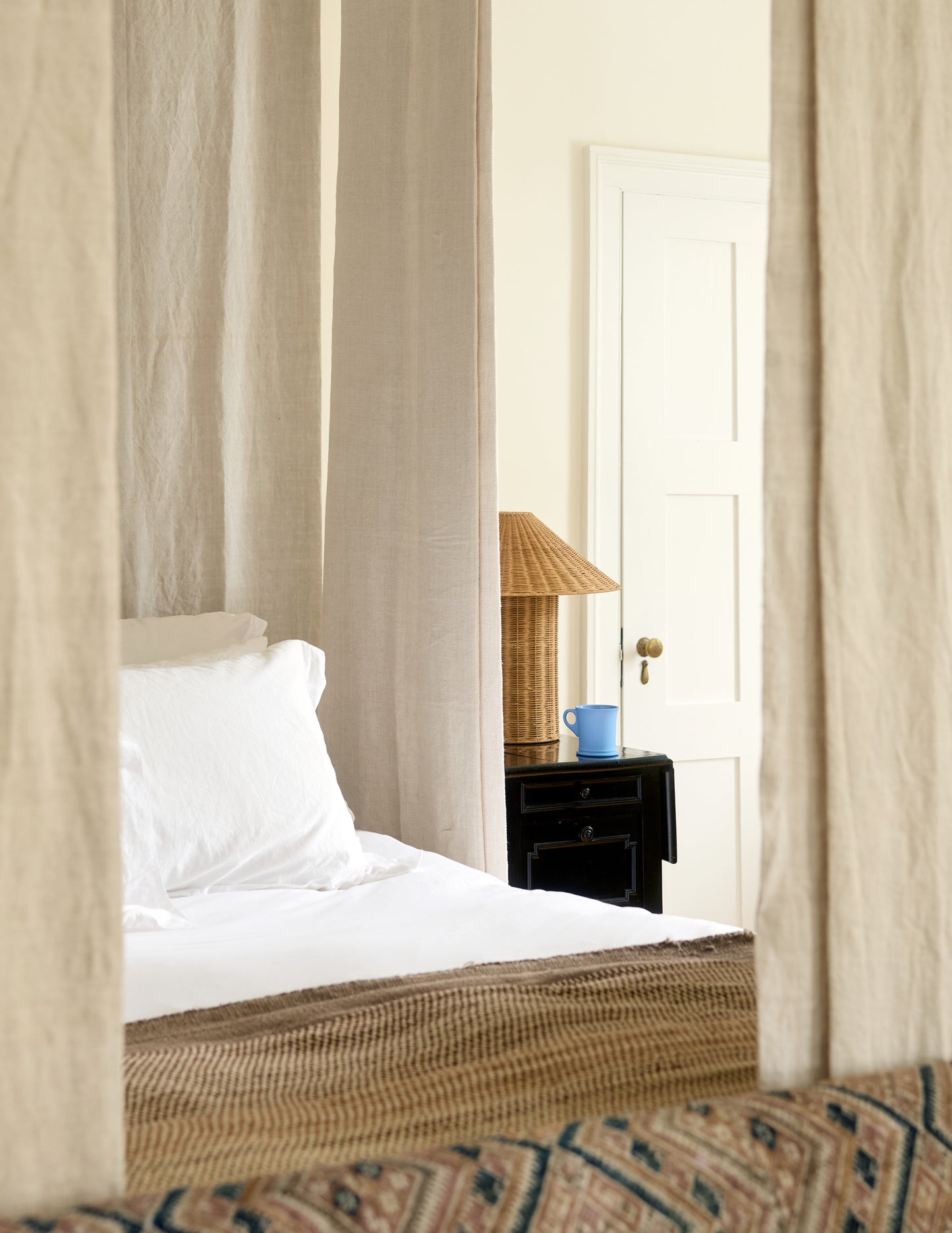 Bedroom with curtains, bed, nightstand, and lamp.