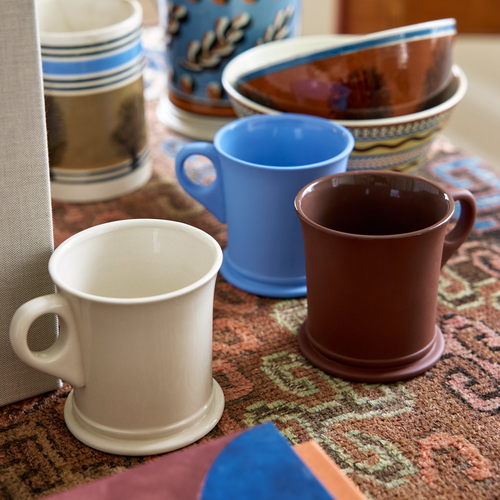 Collection of ceramic mugs and bowls on a textured surface