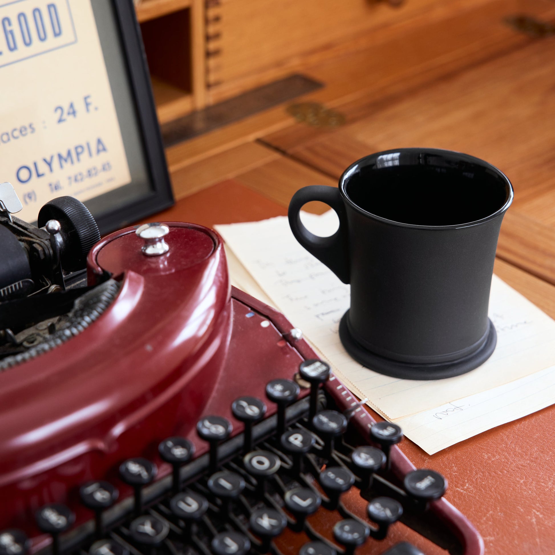 Red typewriter with a black mug on a wooden desk